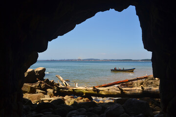 a cave on a beach and a fisherman boat