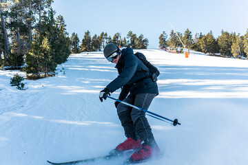 A boy skidding on the snow on skis.