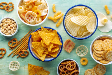 Salty snacks. Party food on a blue background. Potato and tortilla chips, crackers and other...
