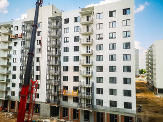 a crane lifts building materials for builders of new houses from monolithic reinforced concrete. Construction of apartments in a new residential complex