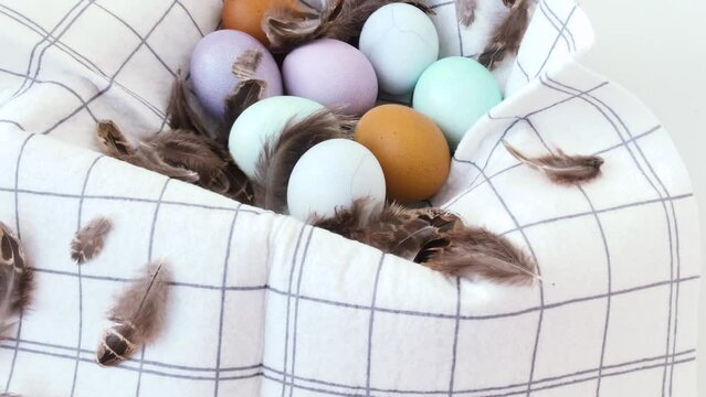 Easter celebrations. Purple, turquoise and brown chicken eggs. Easter eggs in a wooden box with a stylish napkin and brown feathers. 
