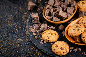 Cookies with pieces of milk chocolate on a stone board. 