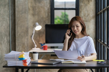 Asian businesswoman working with financial documents, discussing with clients with smartphone and laptop computer on table, analysis plan, financial report. Business plan. Investment finance concept.