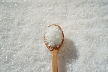 Spoon of coarse salt with coarse salt background	
