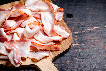 Strips of bacon on a cutting board. 