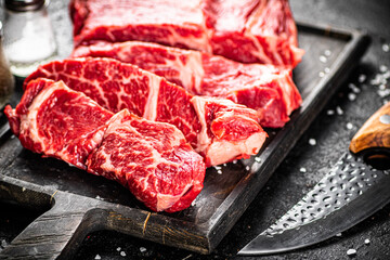 Raw beef on a cutting board with a knife. 