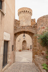 Arco de piedra en el interior de la muralla del Castillo Vila Vella de Tossa de Mar dando la bienvenida a una pequeña plaza con antiguas farolas para iluminarla.