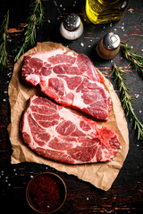 Raw pork steak on paper with rosemary.