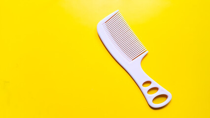 Pink plastic hair comb isolated on yellow background