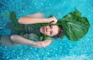 portrait of a sensual seductive woman in water between large green plant leaves, in spa wellness pool. skin care concept