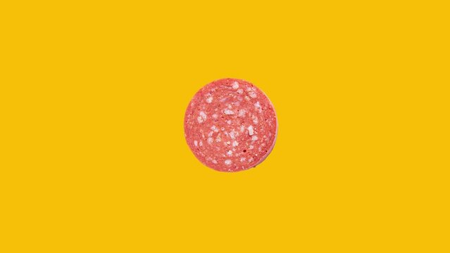 Slice of sucuk rotation on yellow background. Turkish meat product sucuk.