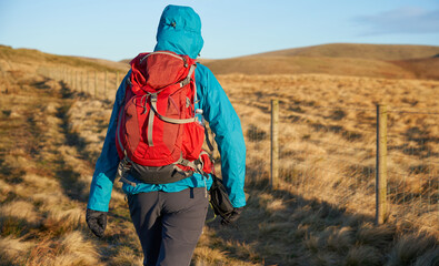 A close up of a hiker below the summit of Swineside Law on a sunny winters morning sunrise in the...