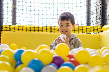 kid having fun in play center pool with colorful many balls.happy smiling child preschooler boy...