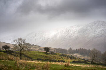 The snow covered summits of Ill Bell and Yoke from Nanny Lane dissappearing into the cloud on a cold winters morning in the Lake District Cumbrian Mountains, England, UK.