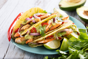 Mexican tacos with shrimp,guacamole and vegetables on wooden table