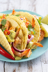Mexican tacos with shrimp,guacamole and vegetables on wooden table