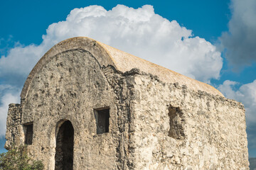 An abandoned Greek chapel against a blue sky with clouds is located on a mountain in an abandoned ghost town near Fethiye in Turkey. Site of the ancient Greek city of Karmilissos from the 18th century