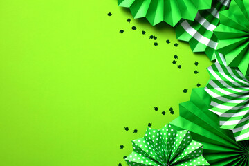 Saint Patrick's Day flat lay composition with green paper fans and confetti on green background. St Patricks Day banner design, greeting card template, party invitation mockup