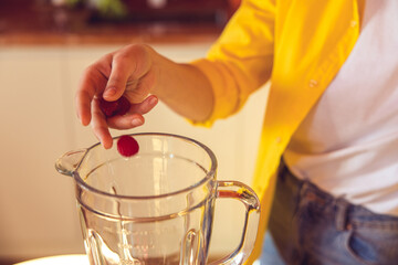 Fototapeta na wymiar Close up of a female hand putting raspberry to the glass
