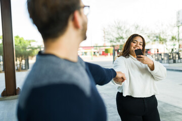 Chubby woman holding hands with her boyfriend and taking pictures