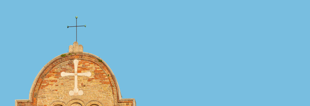 Banner with a Christian Cross at the top of an ancient Church in Venice, Italy, with copy space solid blue sky background