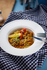 Spaghetti with shrimps, lemon and microgreen. Lunch in a deep white plate, close-up. Pasta with seafood, tomatoes and salad.