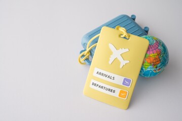 Yellow bag tag, blue suitcase travel bag and globe on white background copy space. Travel around...