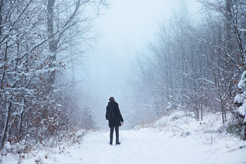 kobieta spacerująca po zimowym lesie we mgle, turysta w lesie