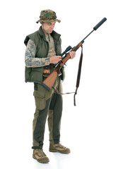 Fifty-year-old man in hunting uniform posing in studio, isolated on white background. Full length portrait of a mature hunter charges the shotgun.