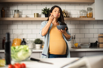 Beautiful pregnant woman having healthy breakfast. Happy woman eating porridge. © JustLife