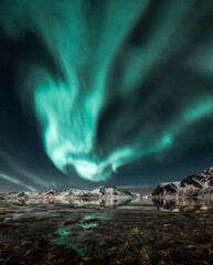 Fototapeta na wymiar Northern lights, Aurora borealis over amazing landscape in Lofoten, Norway with mountains in background, Absolutely stunning and beautiful lights on the sky