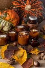 Soy candles burn in glass jars. Tree leaves, pumpkin. Comfort at home. Candle in a brown jar. Scent and light. Scented handmade candle. Aroma therapy. Autumn mood. Cozy home decor in fall.