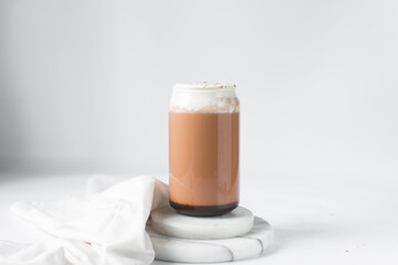 Mocha latte with whipped cream in a can shaped glass, iced mocha with foam and chocolate syrup	