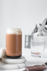 Mocha latte with whipped cream in a can shaped glass, iced mocha with foam and chocolate syrup