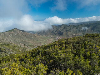 View from Baracan mountain. Green forest, hills and valley with terraced fields and village Las Portelas at Park rural de Teno, Tenerife, Canary Islands, Spain. sunny day, blue sky