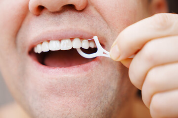 a man's mouth close-up. a man brush your teeth plastic toothpick with dental floss. concept of...