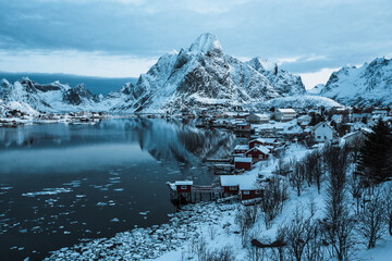 Morning sunrise in Reine, unbelievable view on small fishing village in Lofoten, Norway, Epic snowy mountains and red cabins with water, beautiful background picture from wild nature 