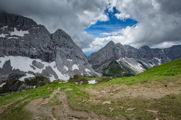 Fototapeta na wymiar Mountain hiking Trail Road. Grey sky before thunderstorm. Between Italy and Austria: near Volaia Lake Raunchkofer Mountain (Lago di Volaia Monte Rauchkofel)