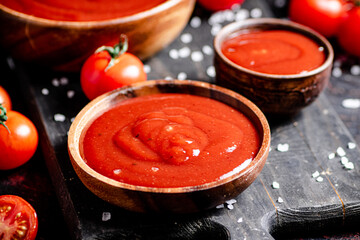 Tomato sauce on a wooden cutting board with pieces of salt. 