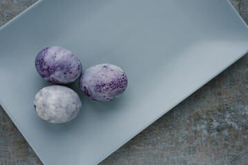Cosmic-colored painted easter eggs on gray rectangular plate. Easter concept in minimalist style