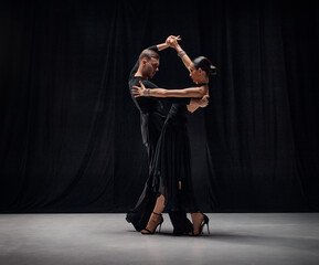 Deep attentive look. Man and woman, professional tango dancers performing in black stage costumes...
