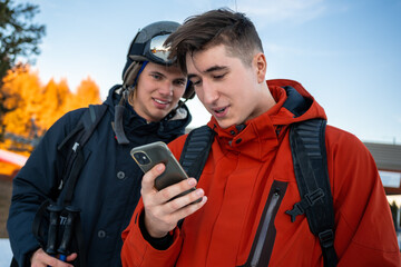 Two boys in ski clothes looking at the phone.