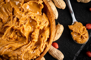 Peanut butter on a stone board with peanuts in the shell. 