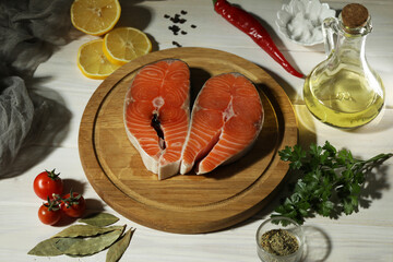 Fresh salmon steak with ingredients on dark wooden background