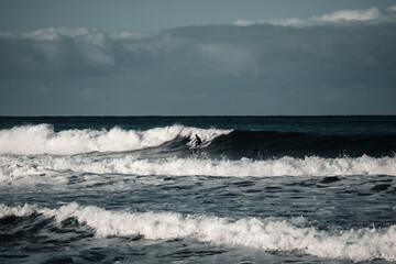 Arctic surfer in Unstad beach, Lofoten, Norway during cold winter time with big waves 