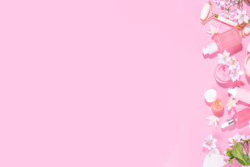 Spring skin care cosmetics flat lay. Beauty facial care cosmetics: serum, cream, mask on pink sunny background with spring blossom flowers, top view copy space
