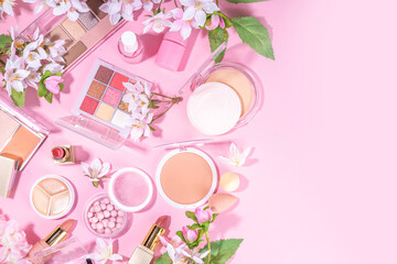 Spring professional makeup flat lay. Spring make up set on pink background. Different make-up cosmetics, beauty accessories flat lay with spring blossom flowers top view copy space