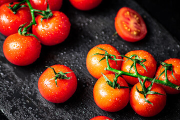 Fresh tomatoes on a branch on a stone board.