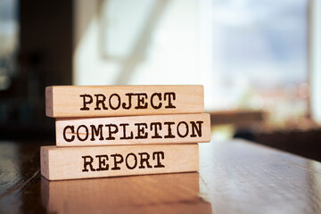 Wooden blocks with words 'PROJECT COMPLETION REPORT'.