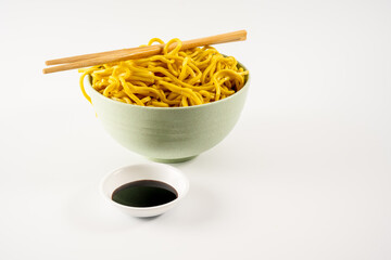 simple bowl of egg noodles  with a dish of dark soy sauce isolated on a white background